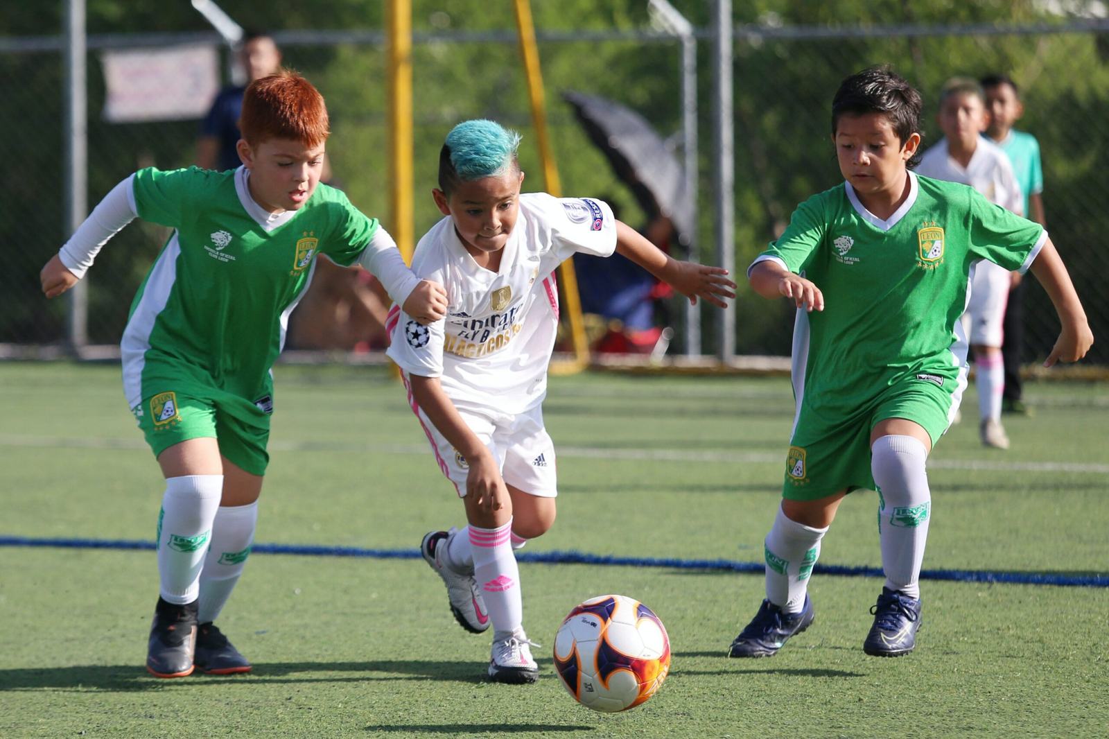 芝生のグラウンドでサッカーの試合をする子どもたち